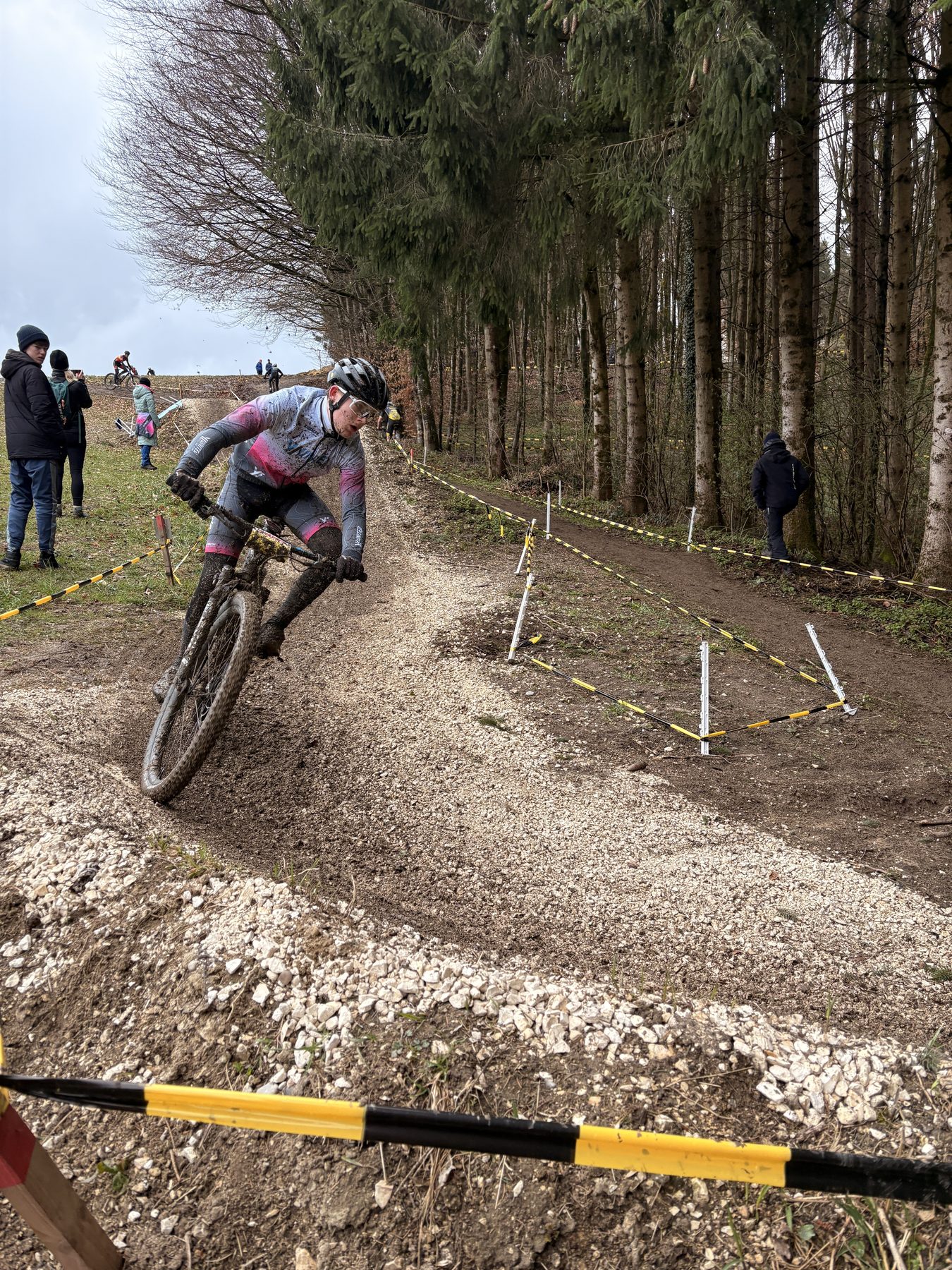 Schlammbedecktes Teammitglied fährt im Winterrennen eine steile Schotterrampe hinauf.