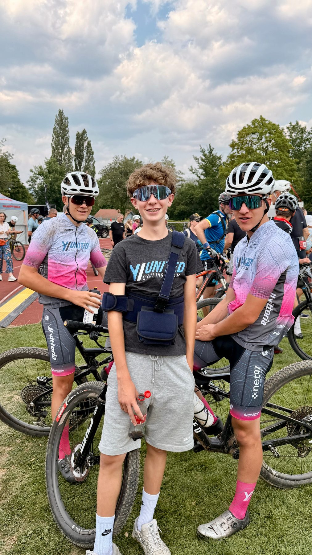 Zwei Jugendliche im Teamtrikot stehen mit ihren Mountainbikes im Fahrerlager und unterhalten sich.